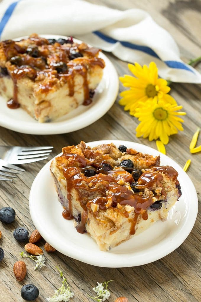Blueberry Bread Pudding Recipe | Blueberry Bread Pudding | Easy Bread Pudding #blueberry #breadpudding #dessert #ezlod Two pieces of blueberry bread pudding on plates with salted caramel on top.