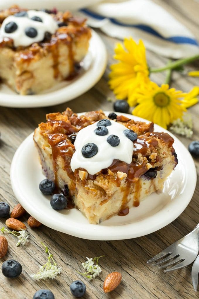 Blueberry Bread Pudding Recipe | Blueberry Bread Pudding | Easy Bread Pudding #blueberry #breadpudding #dessert #ezlod Slices of bread pudding on plates, topped with caramel and fresh berries.
