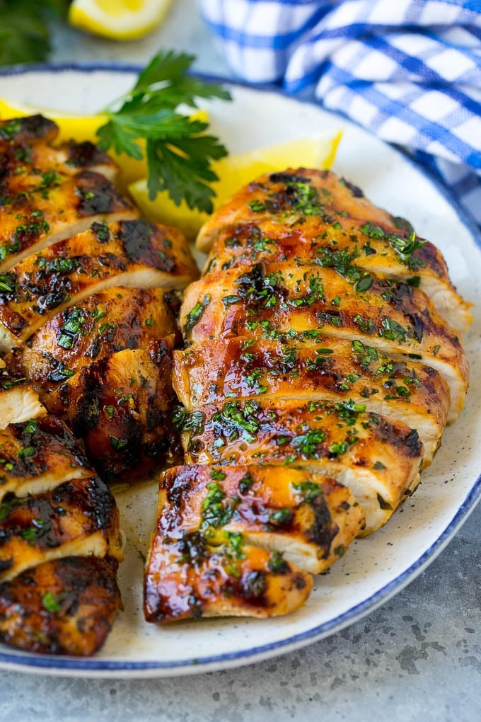 Grilled Chicken Breast Recipe | Marinated Chicken Breast | Chicken Marinade #chicken #grilling #marinade #summer #dinner #ezlod Sliced grilled chicken breast garnished with herbs and lemon.