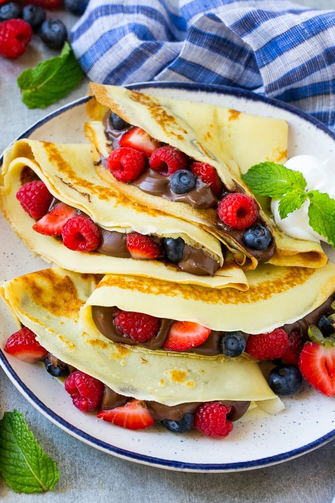 Nutella Crepes Recipe | Easy Crepes Recipe | Blender Crepes | Berry Crepes #crepes #nutella #nutellacrepes #blendercrepes #breakfast #ezlod A platter of crepes served with whipped cream.