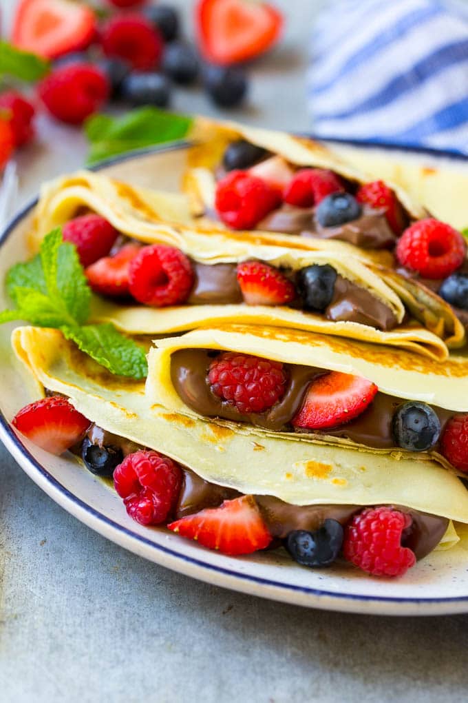 Nutella Crepes Recipe | Easy Crepes Recipe | Blender Crepes | Berry Crepes #crepes #nutella #nutellacrepes #blendercrepes #breakfast #ezlod A plate of Nutella crepes with strawberries, blueberries and raspberries.