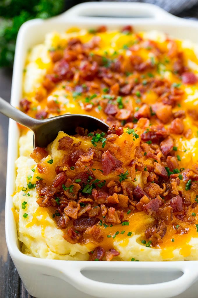 Loaded Mashed Potato Casserole Recipe | Loaded Potatoes | Bacon Mashed Potatoes | Thanksgiving Mashed Potatoes #potatoes #bacon #cheese #casserole #Thanksgiving #dinner #ezlod A dish of loaded mashed potato casserole with a serving spoon in it.