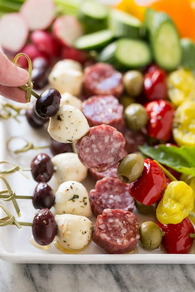 Antipasto Skewers Recipe | Easy Antipasto | Best Antipasto #antipasto #skewers #appetizer #ezlod A hand holding up a skewer of salami, cheese and olives.