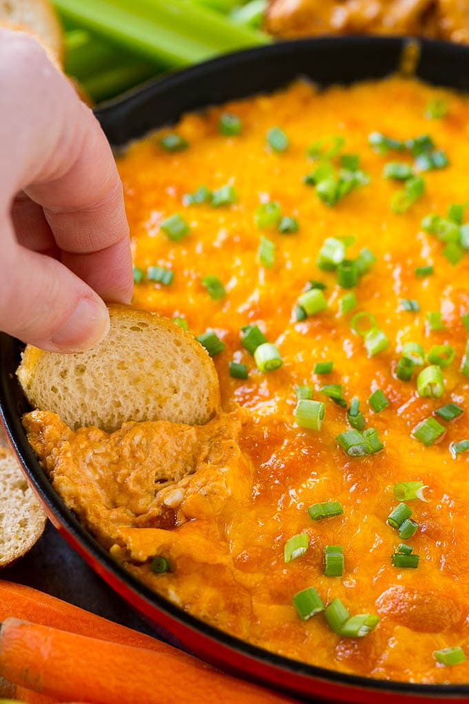 Buffalo Ranch Chicken Dip | Buffalo Chicken Dip | Baked Buffalo Dip | Cheesy Buffalo Dip #buffalowings #buffalochicken #dip #lowcarb #appetizer #ezlod Baked buffalo chicken dip with a baguette slice scooping some out.