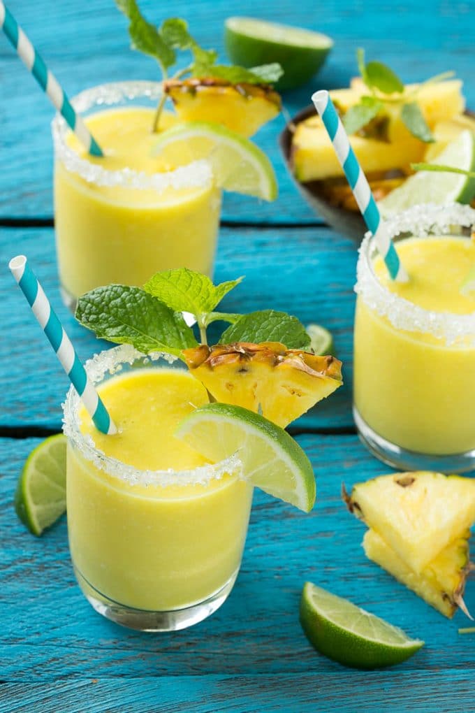 Pineapple Coconut Smoothie Recipe |Tropical Smoothie | Pineapple Smoothie #smoothie #pineapple #coconut #healthy #cleaneating #ezlod Glasses of pineapple coconut smoothie garnished with limes and mint.