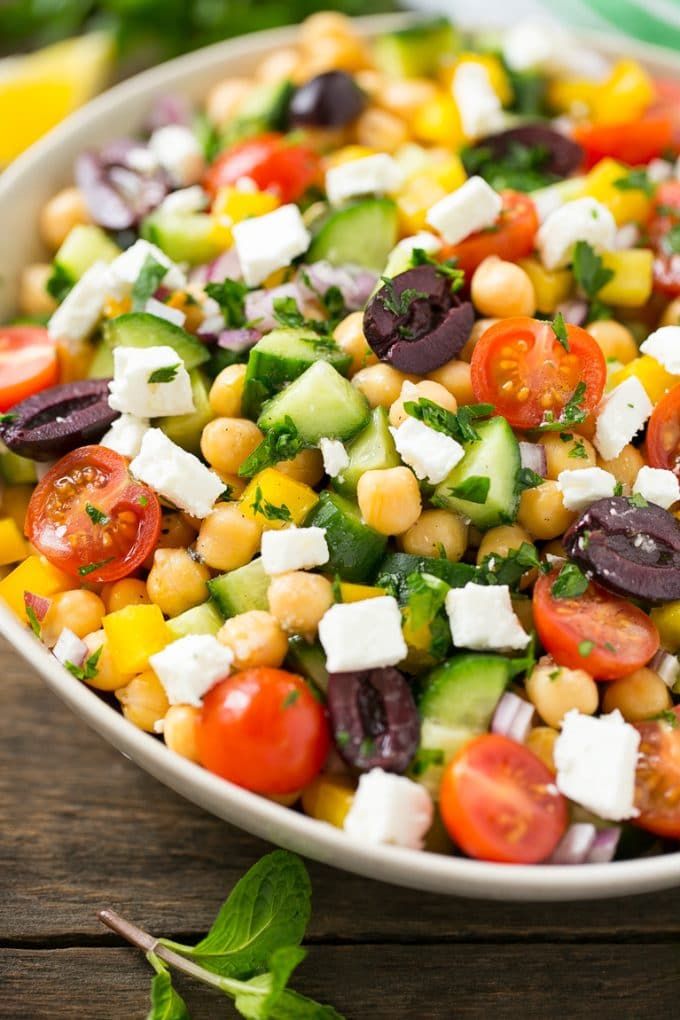 Greek Salad | Chopped Greek salad | Chopped Salad #salad #vegetarian #cheese #chickpeas #lunch #ezlod Cucumbers, chickpeas, olives, tomatoes, peppers and feta cheese in a serving bowl.