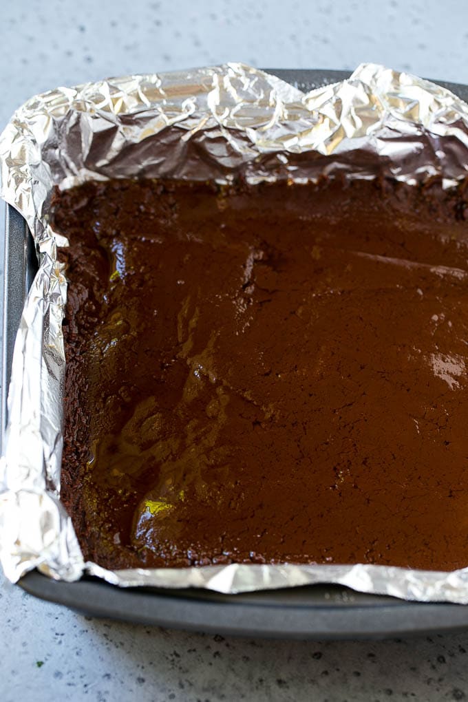 Chocolate Peanut Butter Fudge Recipe | Peanut Butter Cup Fudge | Easy Fudge Recipe #chocolate #peanutbutter #fudge #baking #dessert #ezlod A layer of chocolate fudge in a pan.