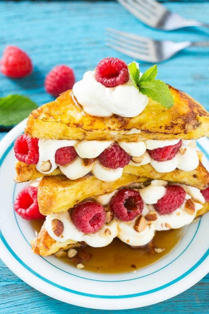 Stuffed French Toast | Cream Cheese Stuffed French Toast | French Toast Recipe #frenchtoast #raspberry #creamcheese #breakfast #brunch #ezlod A plate of cooked brioche filled with cream cheese, berries and almonds.