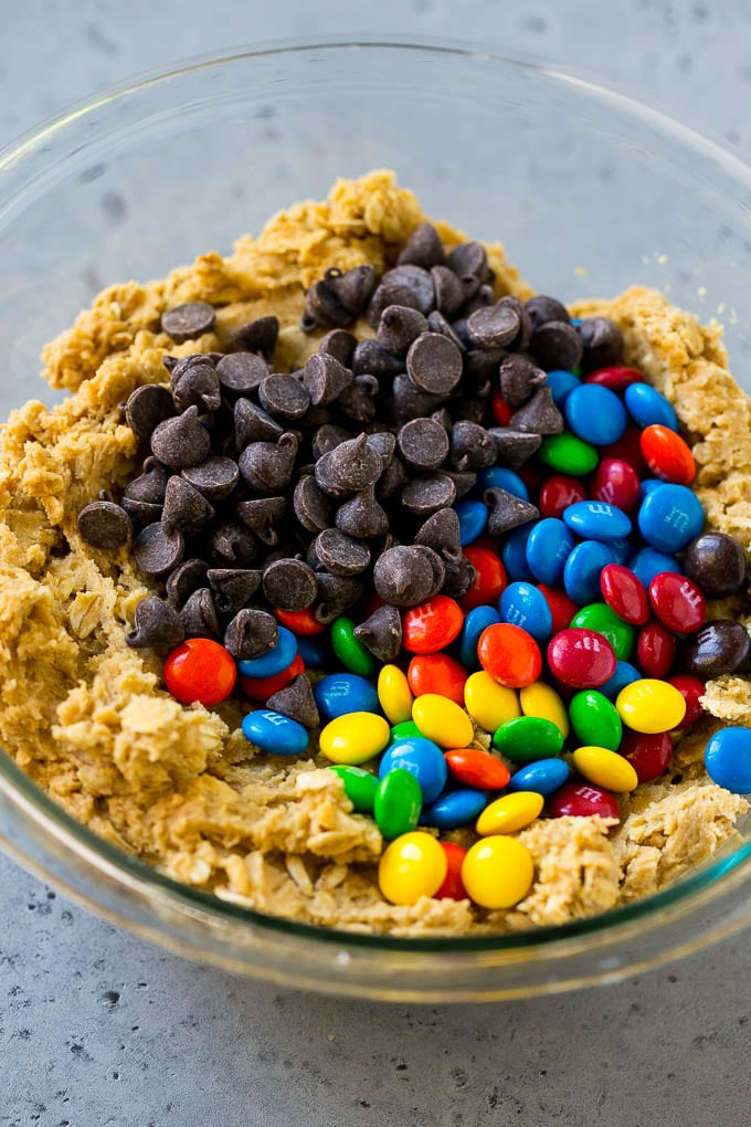 Monster Cookies Recipe | Oatmeal Cookies | Peanut Butter Cookies | M&M's Cookies #baking #cookies #dessert #peanutbutter #chocolate #ezlod Cookie dough with chocolate chips and M&M's on top.