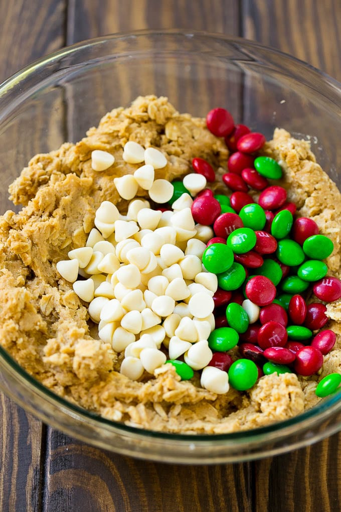 Christmas Monster Cookies Recipe | Oatmeal Cookies | Peanut Butter Cookies | M&M's Cookies #baking #cookies #dessert #peanutbutter #chocolate #ezlod #christmas #sprinkles Cookie dough with red and green M&M's and white chocolate chips.