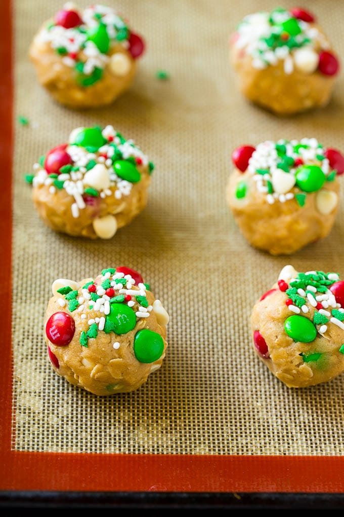 Christmas Monster Cookies Recipe | Oatmeal Cookies | Peanut Butter Cookies | M&M's Cookies #baking #cookies #dessert #peanutbutter #chocolate #ezlod #christmas #sprinkles Balls of cookie dough on a baking sheet.