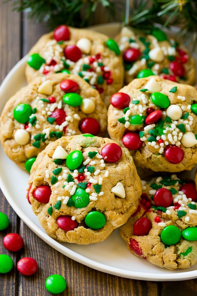 Christmas Monster Cookies Recipe | Oatmeal Cookies | Peanut Butter Cookies | M&M's Cookies #baking #cookies #dessert #peanutbutter #chocolate #ezlod #christmas #sprinkles A plate of Christmas monster cookies which are decorated with M&M's, white chocolate and sprinkles.