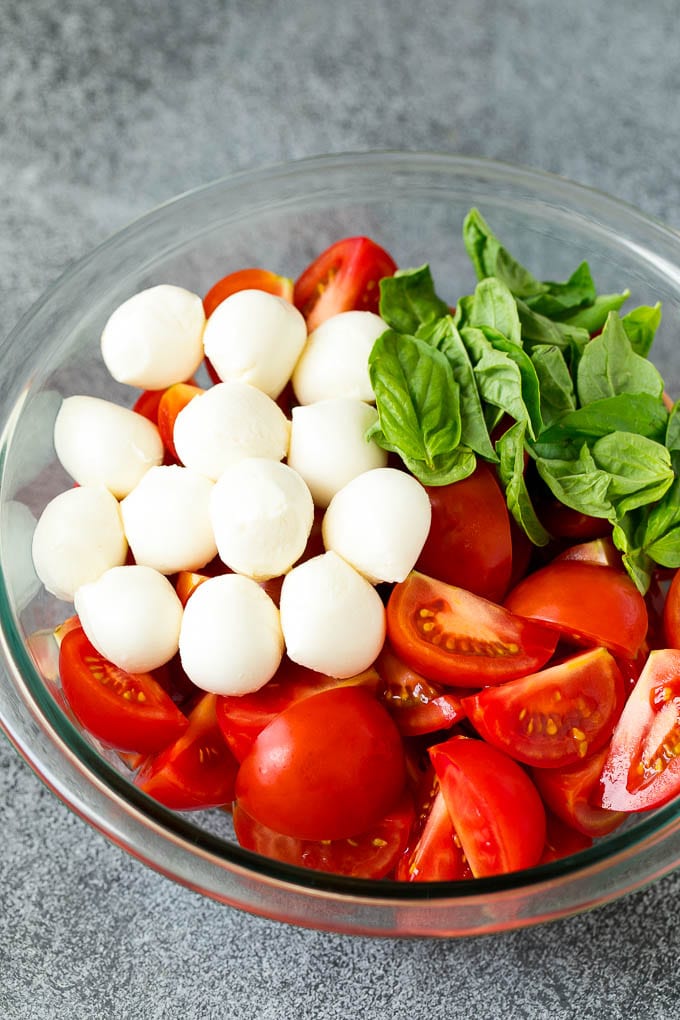Caprese Salad Recipe | Tomato Salad #salad #tomato #mozzarella #cheese #basil #caprese #summer #ezlod Tomatoes, mozzarella and basil in a bowl.