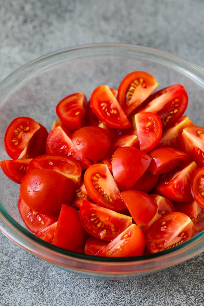 Caprese Salad Recipe | Tomato Salad #salad #tomato #mozzarella #cheese #basil #caprese #summer #ezlod Quartered tomatoes in a bowl.