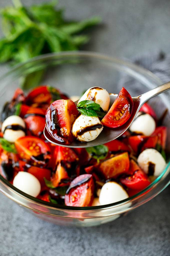 Caprese Salad Recipe | Tomato Salad #salad #tomato #mozzarella #cheese #basil #caprese #summer #ezlod A serving spoon of caprese salad with tomato, mozzarella and basil.