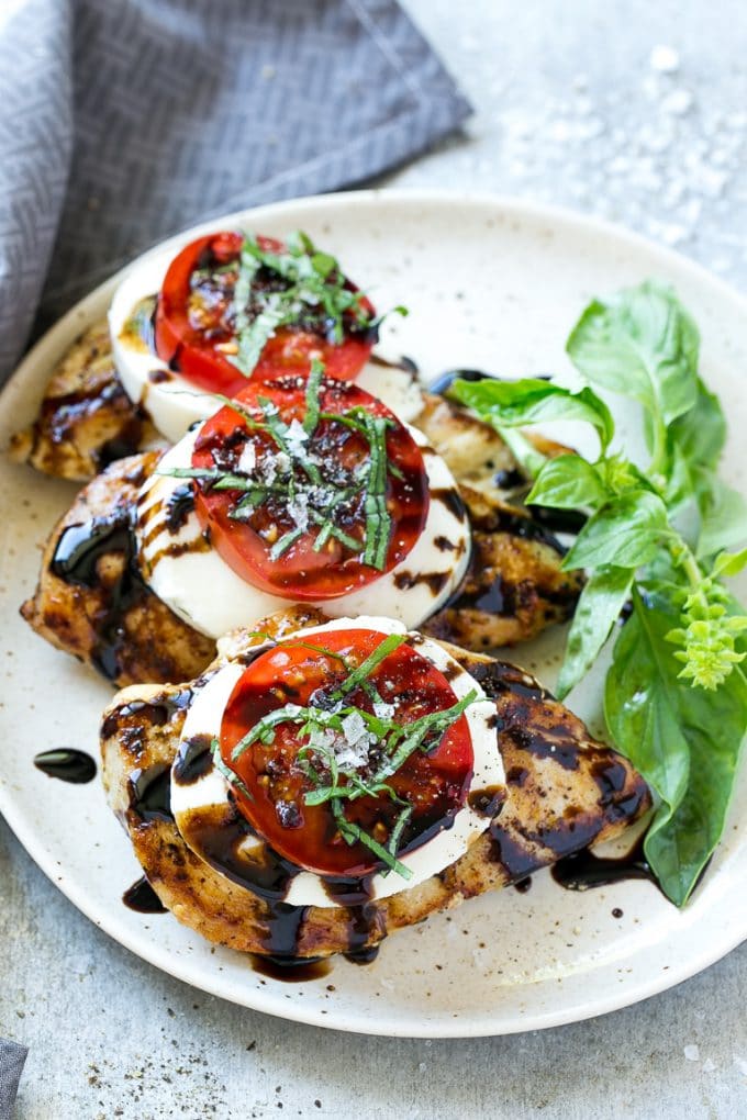 Chicken Caprese Recipe | Grilled Chicken #chicken #caprese #grilling #dinner #tomato #basil #ezlod Grilled chicken on a serving plate topped with sliced tomato and cheese.