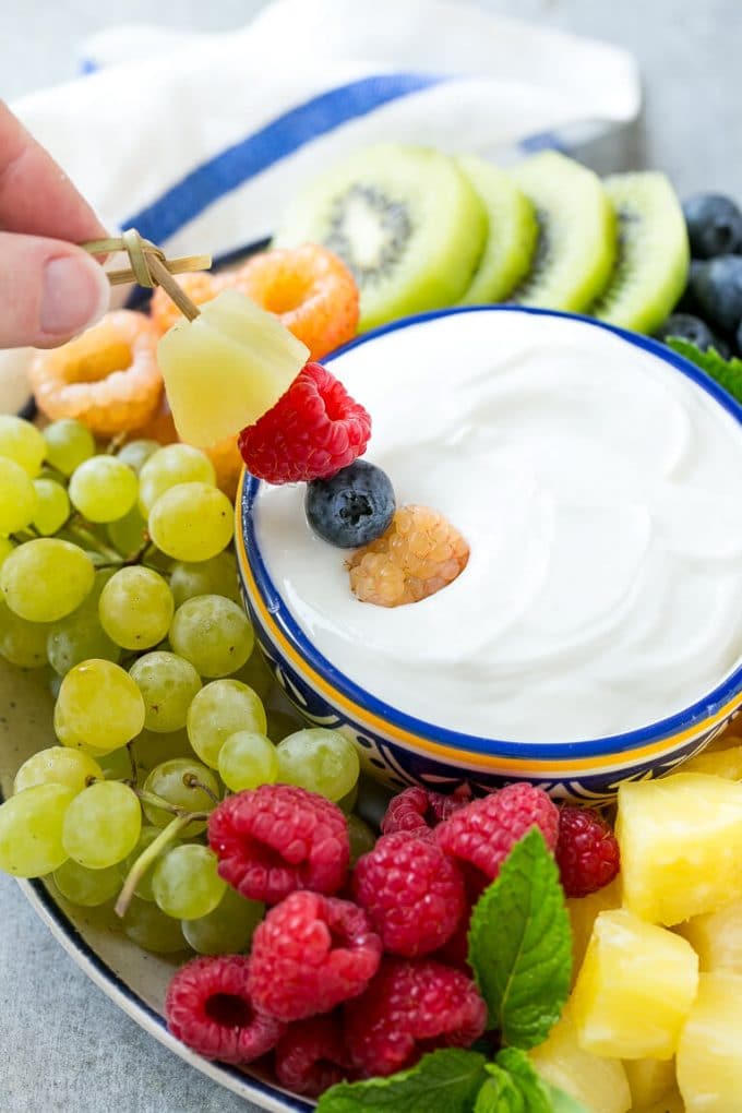 Cream Cheese Fruit Dip | Fruit Recipe | Fruit Dip #fruit #dip #creamcheese #snack #dessert #ezlod A skewer of berries going into a bowl of fruit dip.
