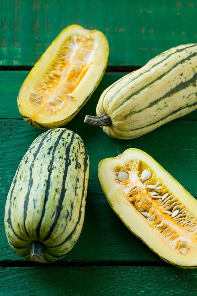 Brown Sugar Delicata Squash Recipe | Roasted Squash | Delicata Squash | Winter Squash Recipe #squash #wintersquash #brownsugar #sidedish #delicatasquash #dinner #ezlod Raw delicata squash on a green board.