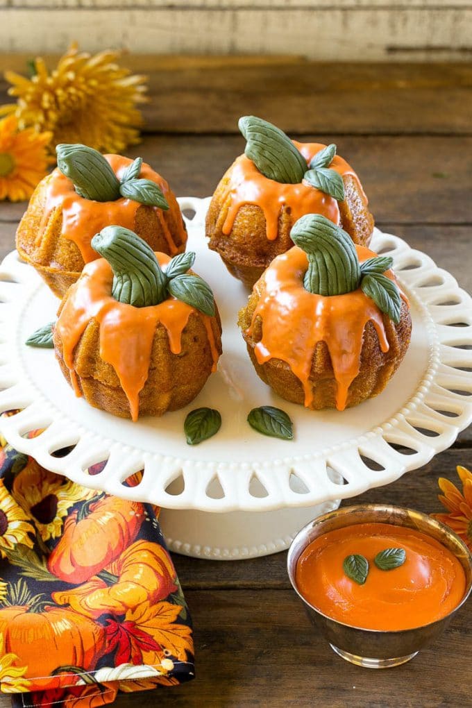 Pumpkin Spice Cake Recipe | Pumpkin Cake | Easy Pumpkin Cake | Thanksgiving Dessert #thanksgiving #pumpkin #cake #pumpkincake #spicecake #dessert #ezlod #holiday Pumpkin spice cake topped with orange glaze and fondant decorations on a serving platter.