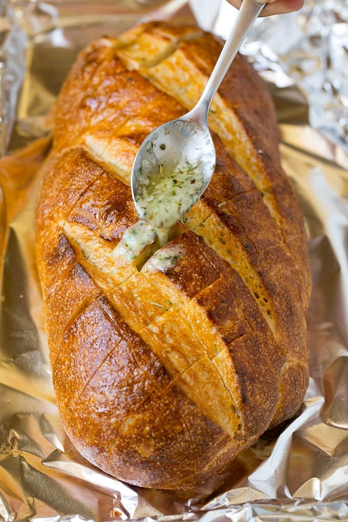 Pull Apart Bread | Garlic Bread | Cheese Bread #bread #garlic #cheese #sidedish #appetizer #ezlod A spoon drizzling garlic butter over a loaf of bread.