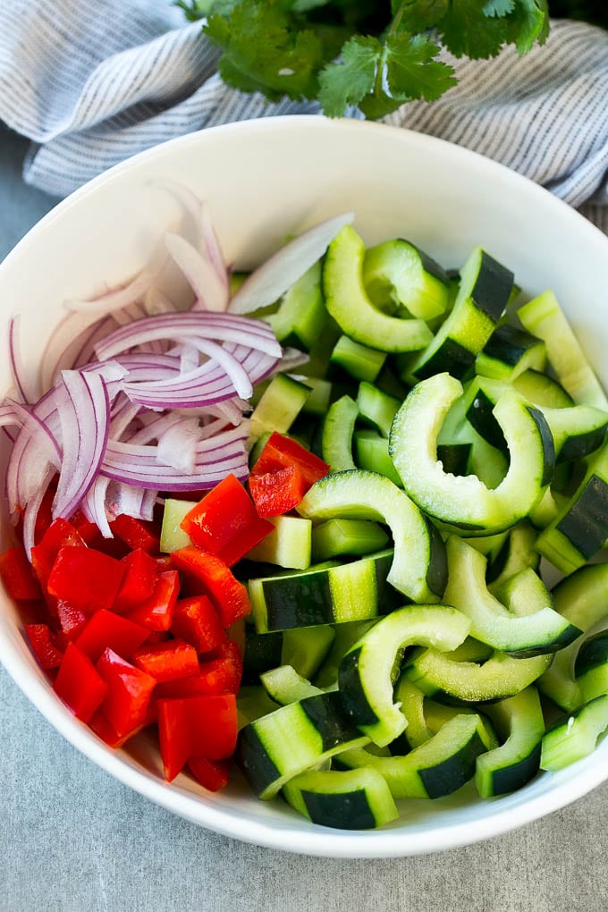 Asian Cucumber Salad Recipe | Sesame Cucumber Salad | Cucumber Salad | Healthy Salad | Healthy Cucumber Recipe #cucumber #cucumbersalad #salad #sidedish #ezlod Sliced cucumbers, red peppers and red onion in a serving bowl.