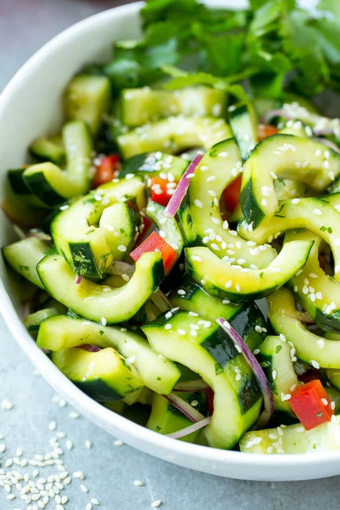 Asian Cucumber Salad Recipe | Sesame Cucumber Salad | Cucumber Salad | Healthy Salad | Healthy Cucumber Recipe #cucumber #cucumbersalad #salad #sidedish #ezlod A bowl of Asian cucumber salad with dressing and sesame seeds on top.