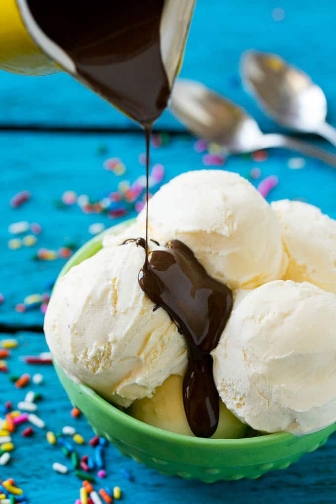 Homemade Magic Shell Recipe | Chocolate Ice Cream Topping | Chocolate Sauce | Hard Chocolate Coating #chocolate #icecream #dessert #ezlod A pitcher of chocolate sauce being poured over vanilla ice cream.