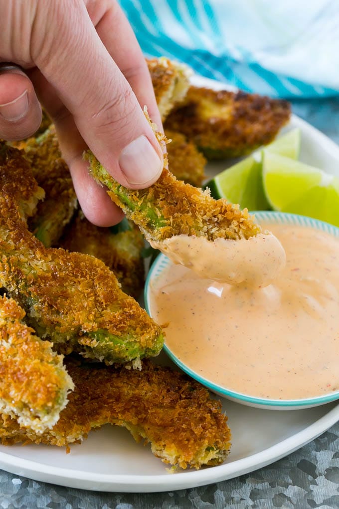 Avocado Fries Recipe | Fried Avocado | Avocado Fritters #avocado #appetizer #snack #ezlod A hand dipping an avocado fry into sauce.