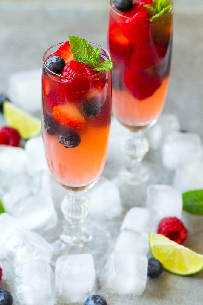 Berry Champagne Punch Recipe | Champagne Cocktail | Lime Cocktail | Berry Punch | Champagne Recipe #champagne #punch #berries #drink #ezlod Two champagne flutes filled with berry champagne punch garnished with berries.