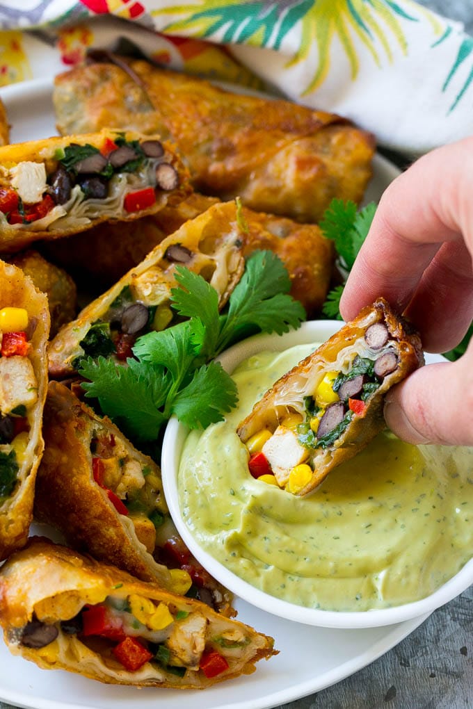 Southwestern Egg Rolls Recipe | Easy Egg Roll Recipe | Mexican Appetizer | Egg Roll Recipe | Southwest Egg Rolls #eggrolls #appetizer #chicken #snack #ezlod A southwestern egg roll being dipped into avocado sauce.