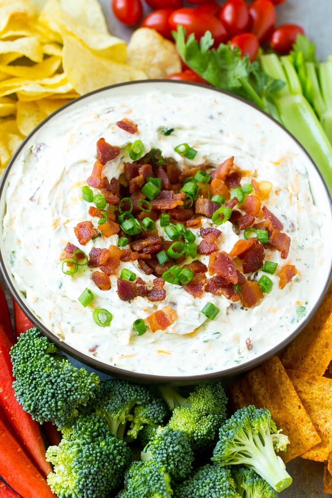 Bacon Ranch Dip Recipe | Homemade Ranch Dip | Easy Dip Recipe | Cheddar Ranch Dip #ranch #ranchdip #bacondip #dip #snack #ezlod #baconranchdip A bowl of creamy bacon cheddar ranch dip surrounded by vegetables and chips.