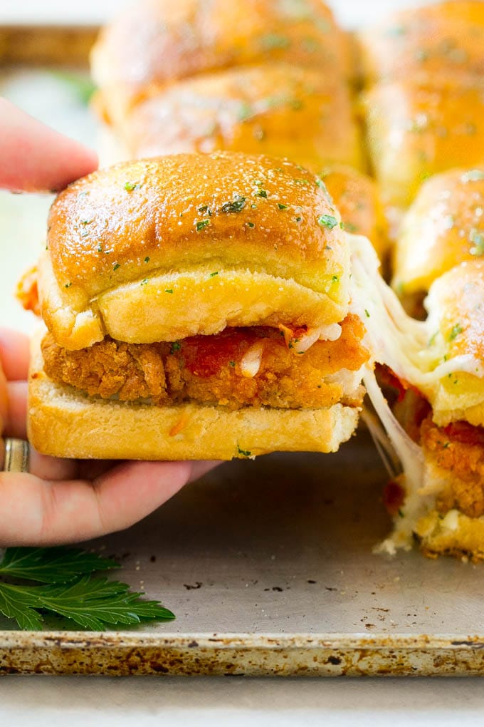 Chicken Parmesan Sliders | Chicken Parmesan Sandwich Recipe | Slider Sandwich Recipe #sliders #chickenparm #chickenparmesan #chickenparmesansliders #dinner #appetizer #ezlod A crispy chicken parmesan slider being pulled away by a hand.