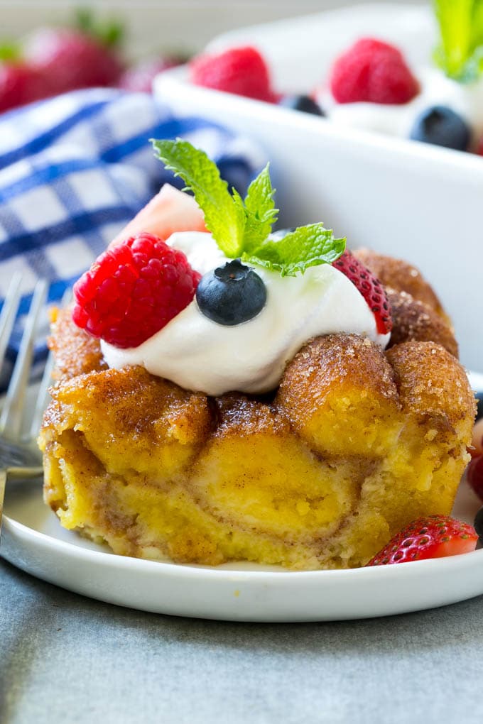 Donut Bread Pudding Recipe | Easy Bread Pudding | Cinnamon Donuts | Make Ahead Breakfast Recipe #breadpudding #donuts #donutholes #breakfast #ezlod Slice of donut bread pudding topped with whipped cream and berries.