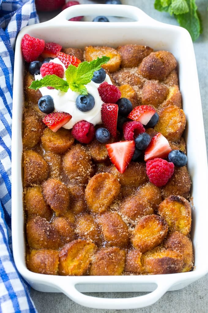 Donut Bread Pudding Recipe | Easy Bread Pudding | Cinnamon Donuts | Make Ahead Breakfast Recipe #breadpudding #donuts #donutholes #breakfast #ezlod A tray of donut bread pudding garnished with whipped cream and berries.