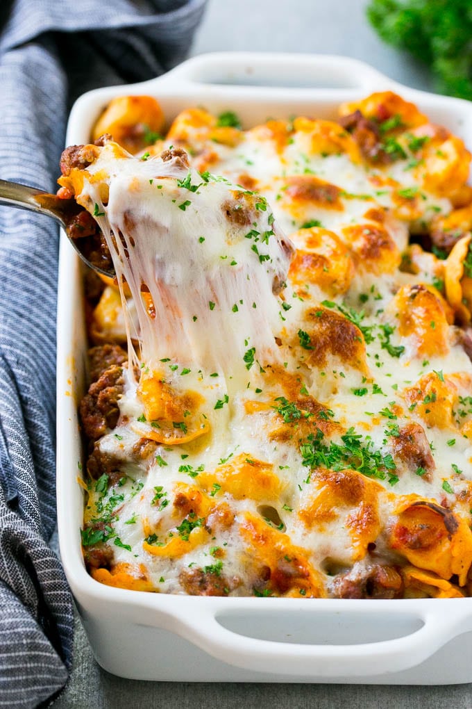 Baked Tortellini with Meat Sauce Recipe | Cheese Tortellini | Tortellini Recipe | Baked Pasta Recipe #tortellini #bakedtortellini #meatsauce #pasta #dinner #ezlod A pan of cheesy baked tortellini with a spoon lifting up a portion.