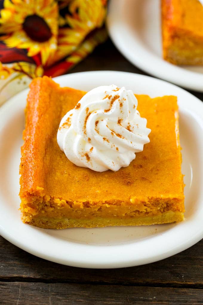 Pumpkin Gooey Butter Cake Recipe | Pumpkin Cake Recipe | Gooey Butter Cake | Pumpkin Dessert | Thanksgiving Dessert #pumpkin #cake #pumpkincake #gooeybuttercake #dessert #ezlod A slice of pumpkin gooey butter cake topped with whipped cream.