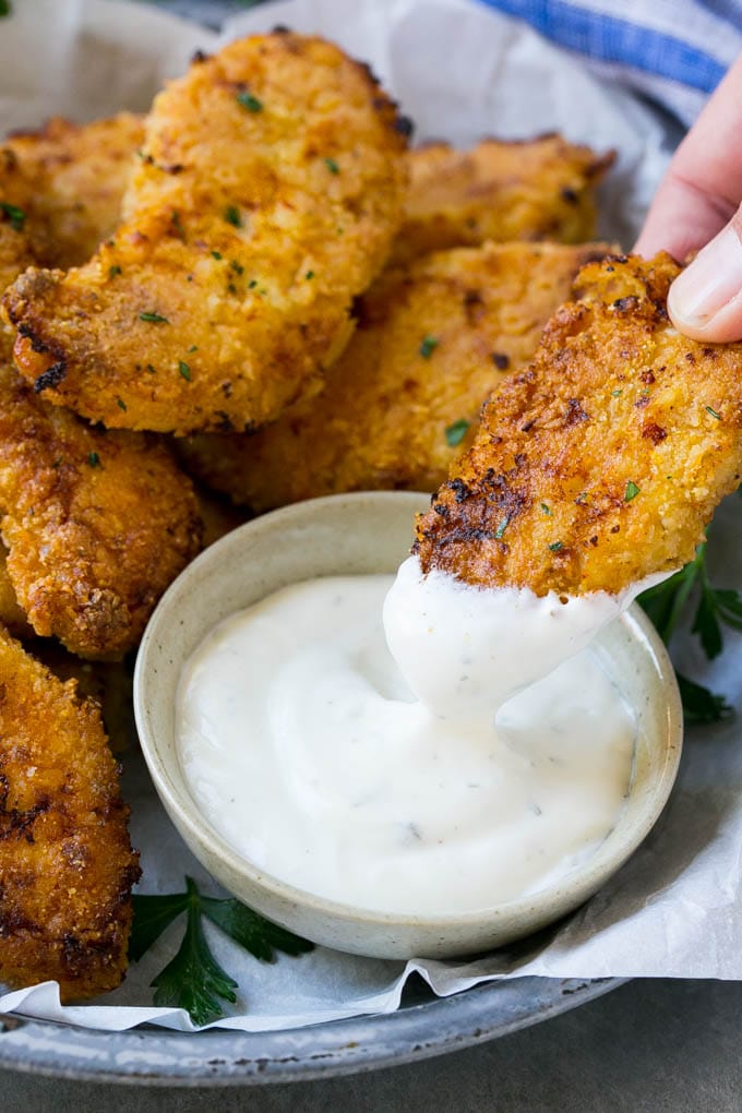 Baked Fried Chicken Recipe | Oven Fried Chicken | Baked Chicken Fingers | Crispy Chicken Fingers #chicken #friedchicken #bakedchicken #ovenfriedchicken #chickenfingers #dinner #ezlod A chicken finger being dipped into ranch dressing.