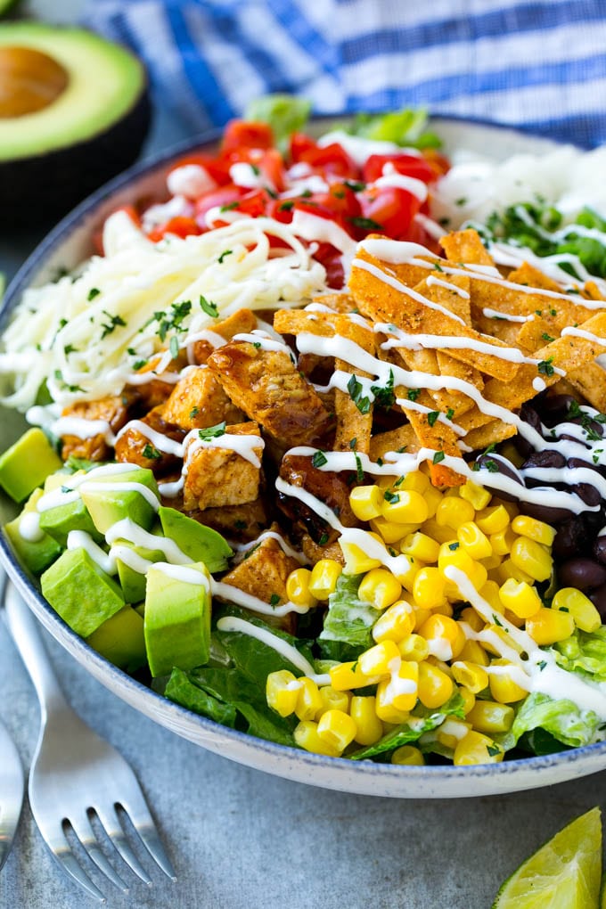 BBQ Chicken Salad Recipe | Chopped BBQ Chicken Salad | CPK Copycat Recipe | California Pizza Kitchen Copycat Recipe | Chicken Ranch Salad #copycat #CPK #BBQchicken #chicken #salad #dinner #ezlod A bowl of BBQ chicken salad topped with a drizzle of ranch dressing.