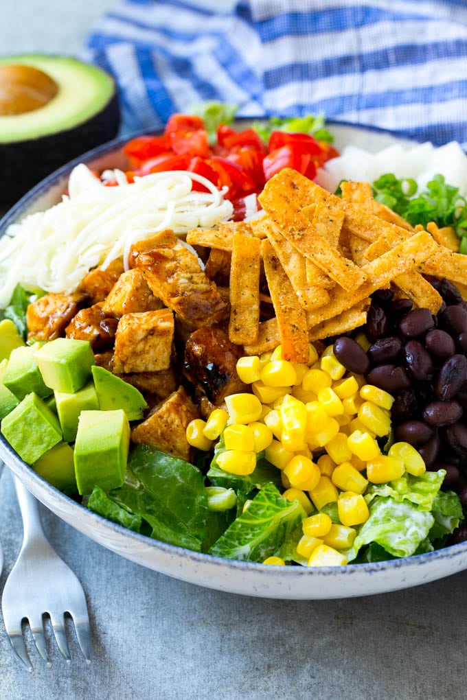 BBQ Chicken Salad Recipe | Chopped BBQ Chicken Salad | CPK Copycat Recipe | California Pizza Kitchen Copycat Recipe | Chicken Ranch Salad #copycat #CPK #BBQchicken #chicken #salad #dinner #ezlod A bowl of salad topped with chicken, tortilla strips, black beans, jiacama, avocado and tomatoes.