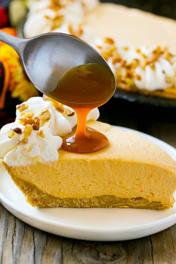 No Bake Pumpkin Cheesecake Recipe | Pumpkin Cheesecake | No Bake Cheesecake | Thanksgiving Dessert | Pumpkin Dessert #nobake #cheesecake #pumpkin #pumpkinpie #pumpkincheesecake #nobakecheesecake #dessert #ezlod A spoon pouring caramel over a slice of pumpkin cheesecake.
