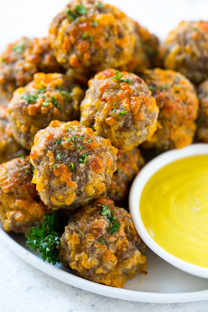 Sausage Cheese Balls Recipe | Sausage Balls Recipe | Bisquick Sausage Balls #sausage #sausageballs #balls #appetizer #cheeseballs #ezlod A pile of sausage cheese balls with a side of honey mustard.