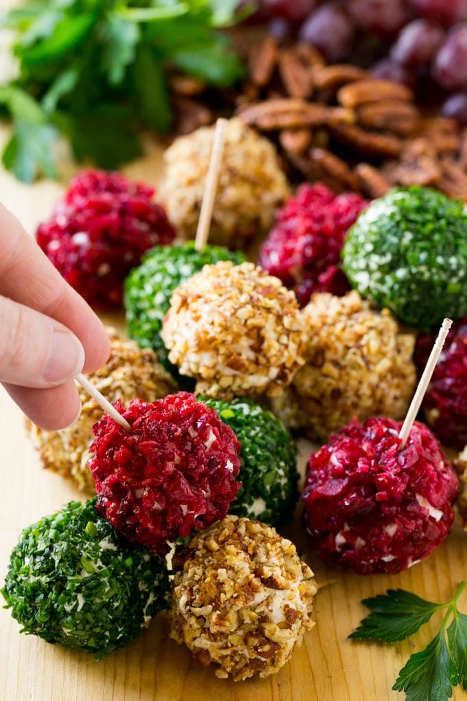 Cheese Ball Bites Recipe | Holiday Cheese Ball Recipe | Pecan Cheese Ball | Cranberry Cheese Ball | Mini Cheese Balls #cheeseball #cheese #appetizer #ezlod A hand reaching for an appetizer crusted in dried craberries.