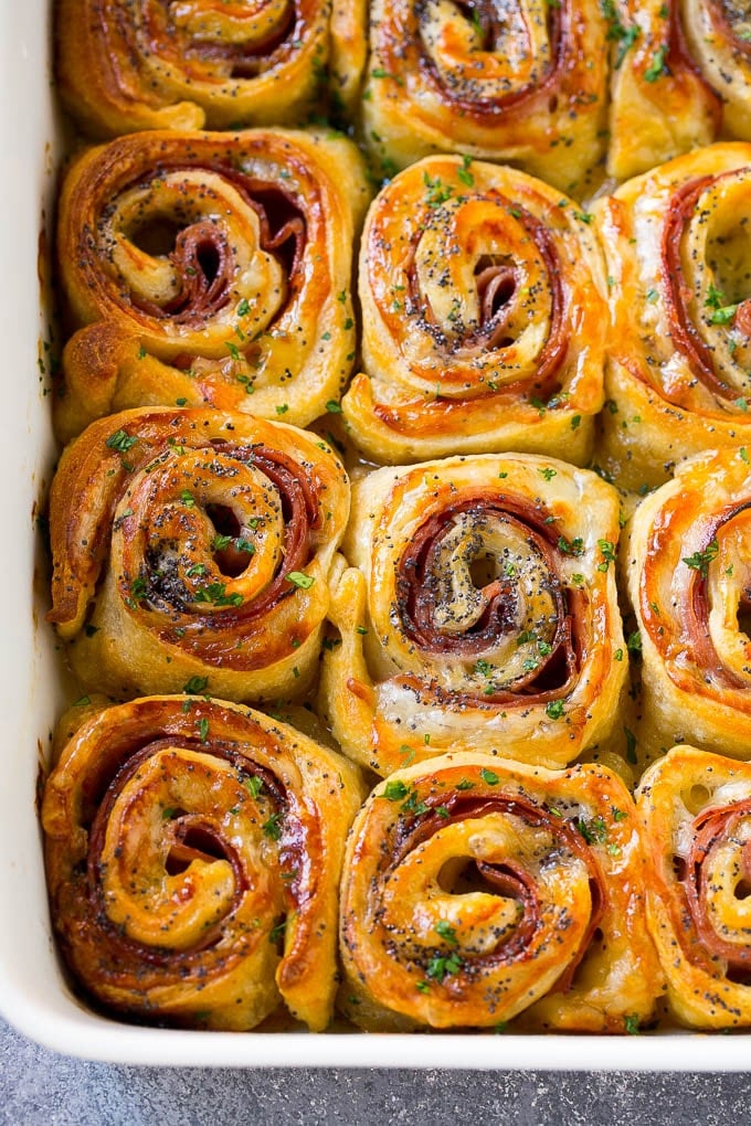 Ham and Cheese Pinwheels Recipe | Ham and Cheese Roll Ups | Ham and Cheese Rolls | Ham and Cheese Bread Rolls #ham #cheese #appetizer #pinwheels #ezlod Ham and cheese pinwheels in a baking dish topped with parsley.