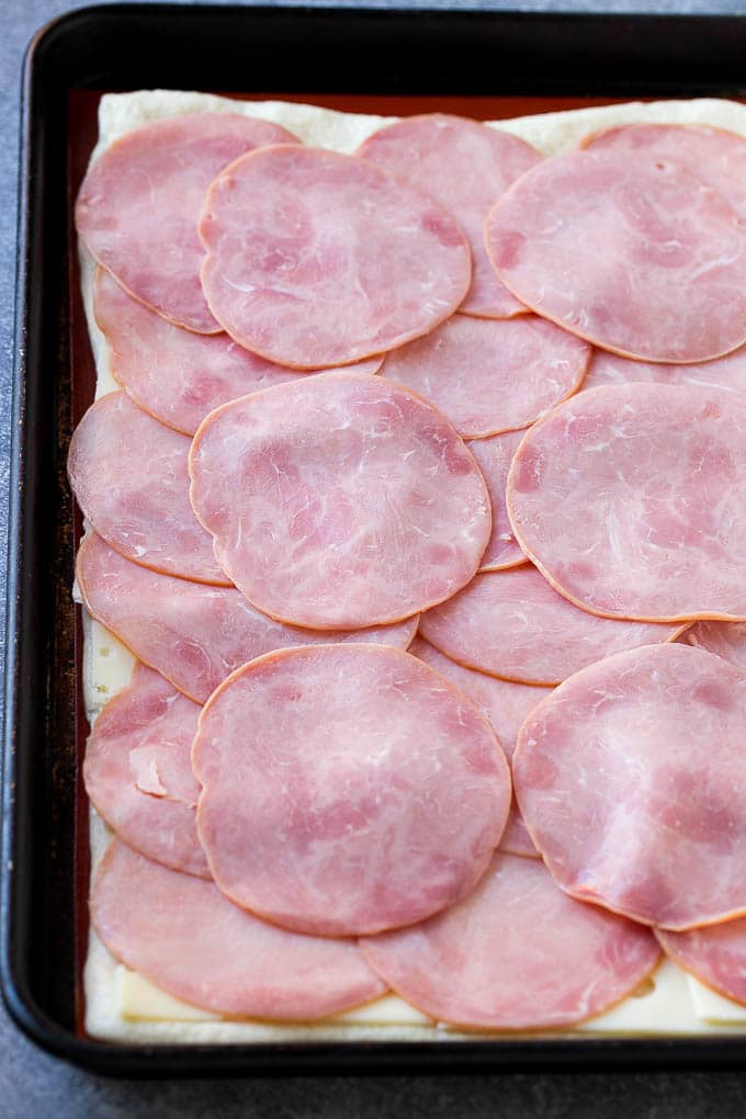 Ham and Cheese Pinwheels Recipe | Ham and Cheese Roll Ups | Ham and Cheese Rolls | Ham and Cheese Bread Rolls #ham #cheese #appetizer #pinwheels #ezlod Slices of ham and cheese on top of dough.
