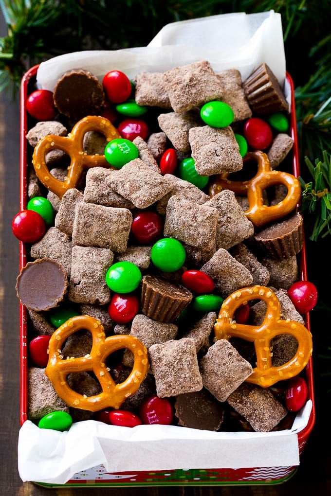 Reindeer Chow | Christmas Chex Mix | Christmas Muddy Buddies | Holiday Chex Mix #chex #chexmix #christmas #holiday #muddybuddies #reindeerchow #snack #ezlod A tin of reindeer chow with chocolate coated chex, M&M's and pretzels.