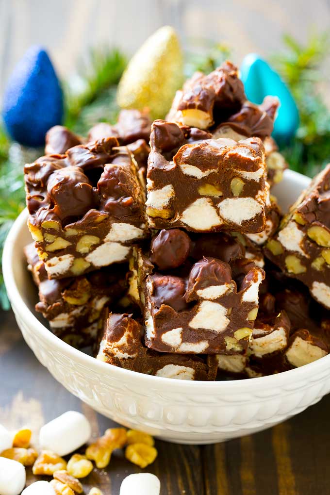 Rocky Road Fudge | Chocolate Marshmallow Fudge | Chocolate Nut Fudge | Microwave Fudge #fudge #chocolatefudge #nobake #chocolate #dessert #rockyroad #ezlod A bowl of fudge squares with holiday decorations in the background.