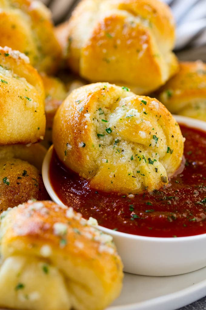 Garlic Knots Recipe | Garlic Rolls | Garlic Butter Rolls | Garlic Bread Recipe #garlic #garlicbread #garlicknots #breadsticks #ezlod A garlic roll being dipped into marinara sauce for a delicious finishing touch.
