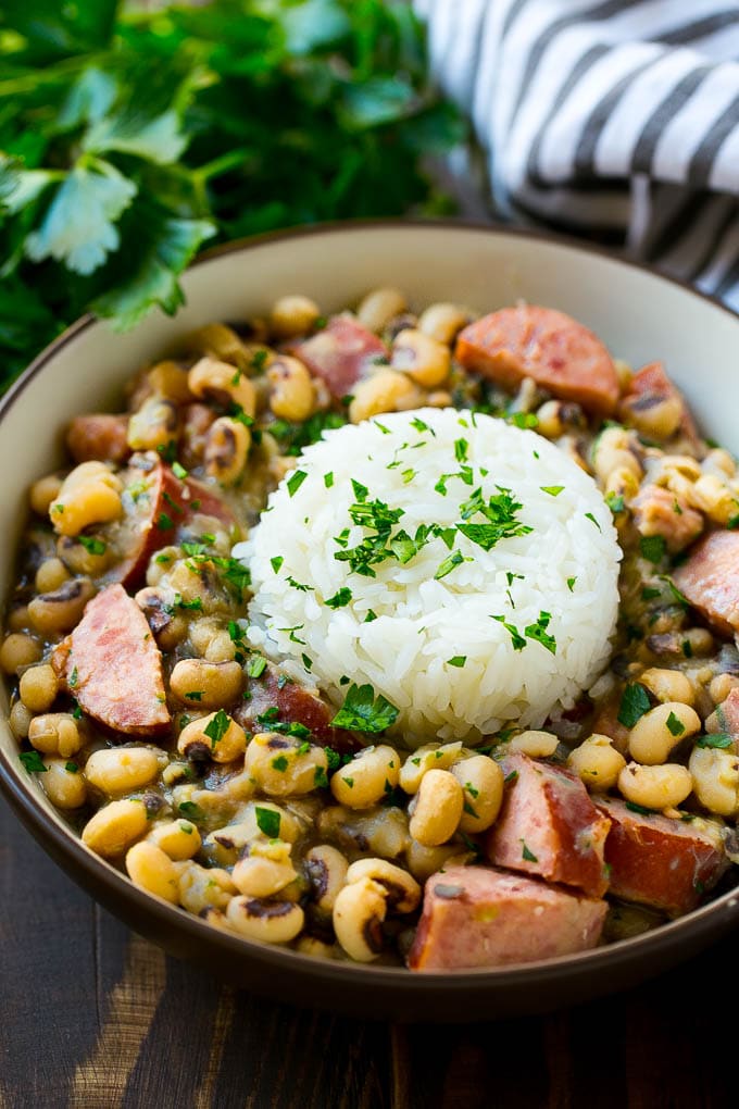 Slow Cooker Black Eyed Peas Recipe | Crock Pot Black Eyed Peas | Southern Black Eyed Peas | Black Eyed Peas with Ham | Black Eyed Peas with Sausage #blackeyedpeas #slowcooker #crockpot #sausage #newyears #dinner #ezlod A bowl of slow cooker black eyed peas with a scoop of rice.