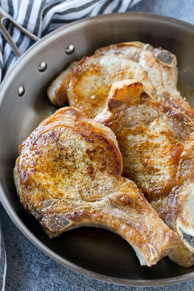 Brown Sugar Pork Chops Recipe | Bone In Pork Chops Recipe | Garlic Butter Pork Chops | Skillet Pork Chops #pork #porkchops #garlic #dinner #glutenfree #ezlod Browned bone in pork chops in a frying pan.