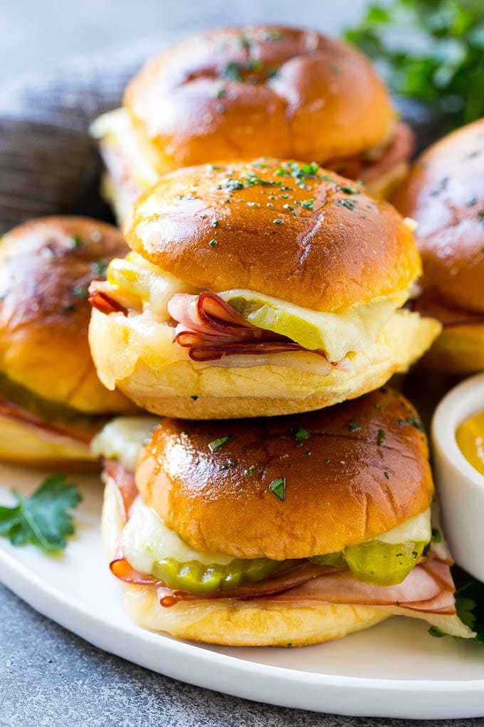 Cuban Sliders Recipe | Cuban Sandwich Recipe | Slider Sandwiches | Ham and Cheese Sliders #sliders #sandwiches #ham #cheese #appetizer #ezlod A pile of cuban sliders filled with ham, cheese and pickles.